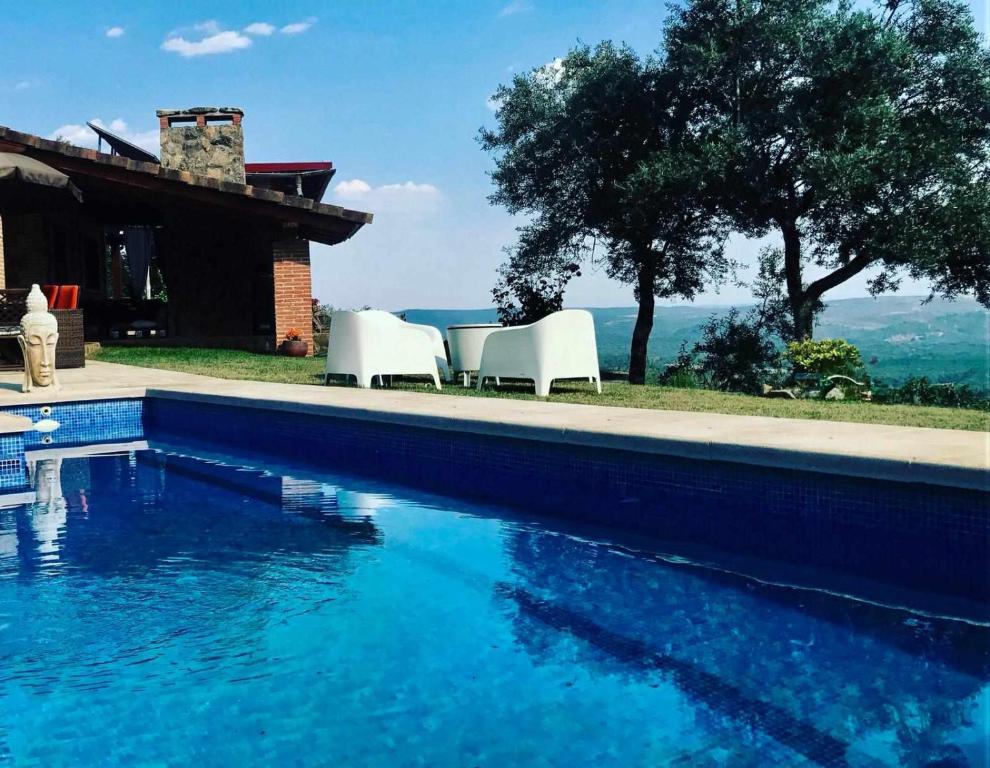 una piscina con 2 sillas blancas junto a una casa en Casa Rural Olivar de Gredos Entorno privilegiado con vistas de ensueño, en Arenas de San Pedro