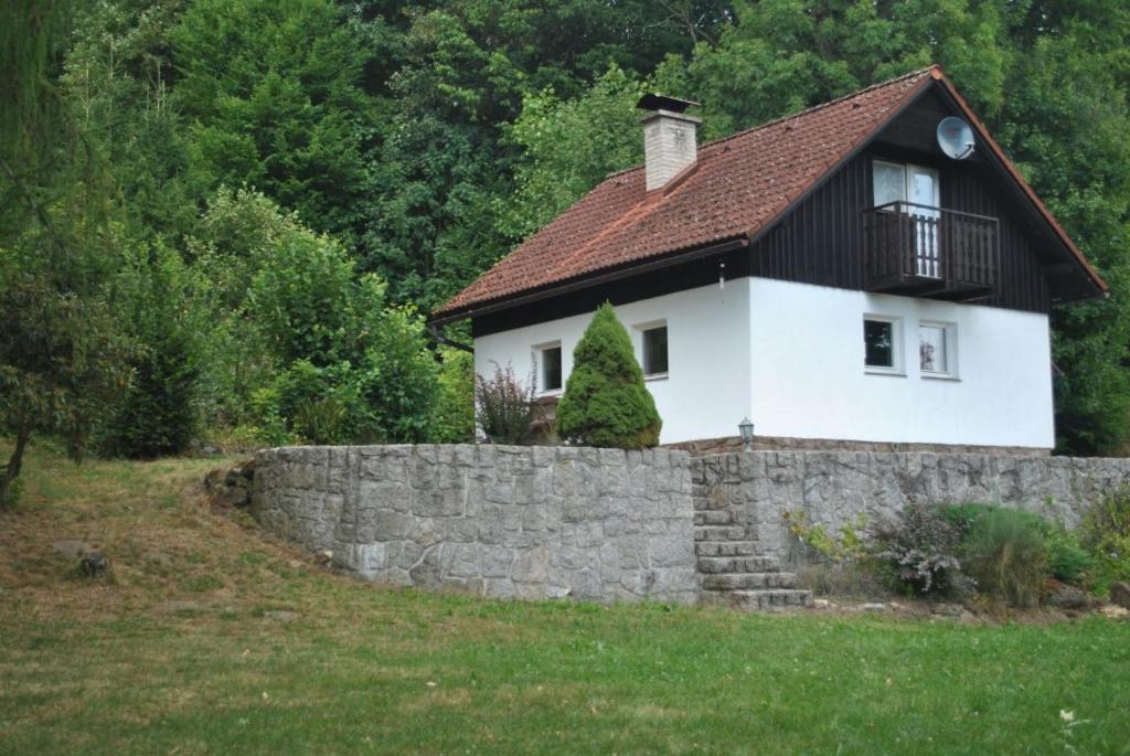 ein weißes Haus mit einem schwarzen Dach und einer Steinmauer in der Unterkunft Snoepie in Víchová nad Jizerou