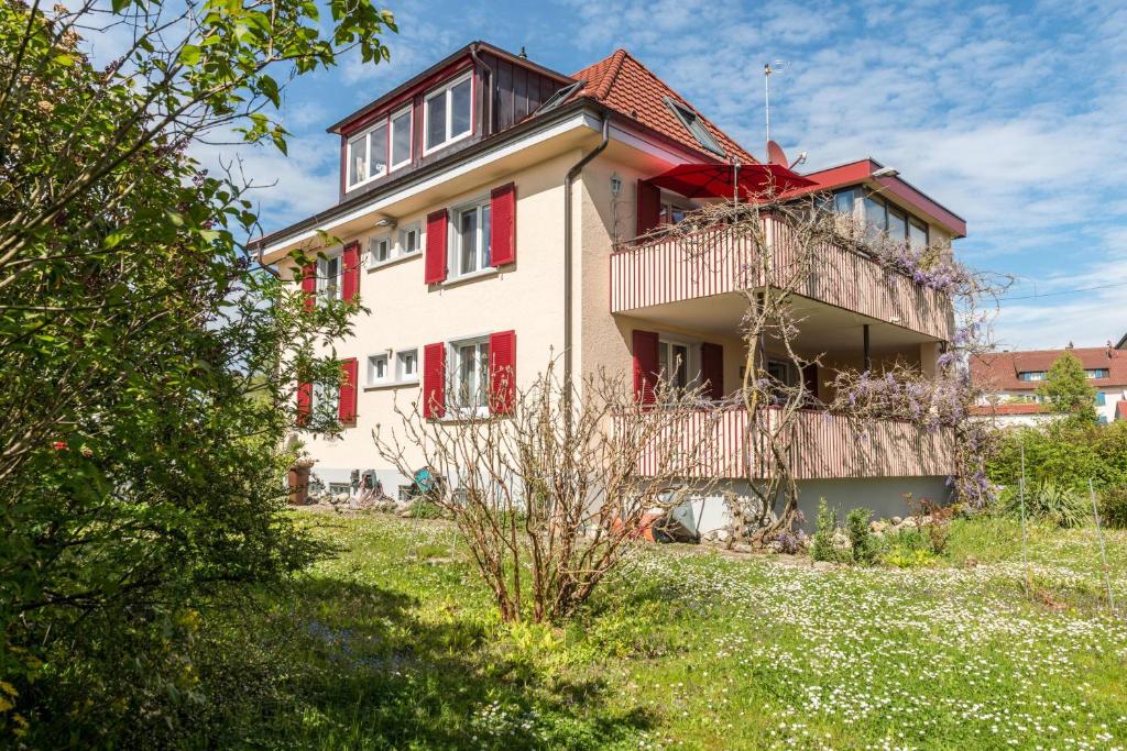 a house with red shutters on the side of it at Flair Ferienwohnung Orchidee in Stockach