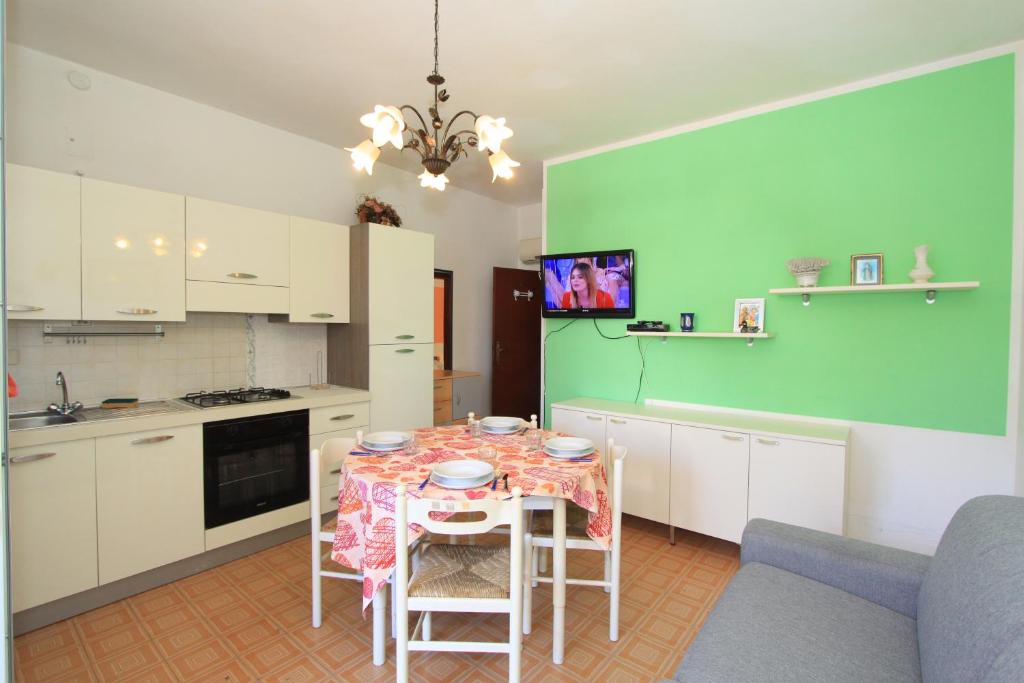 una cocina con mesa, sillas y una pared verde en Appennini Villas, en Lido di Pomposa