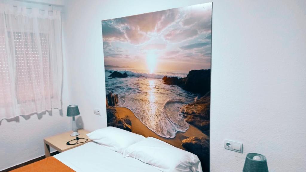 een slaapkamer met een schilderij van de oceaan bij tranquilidad en el centro de la ciudad in Málaga