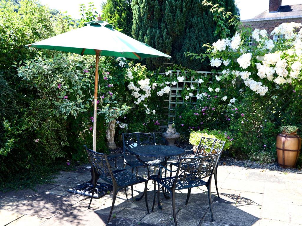 a table and chairs under a green umbrella at The Garden Apartment in Ironbridge