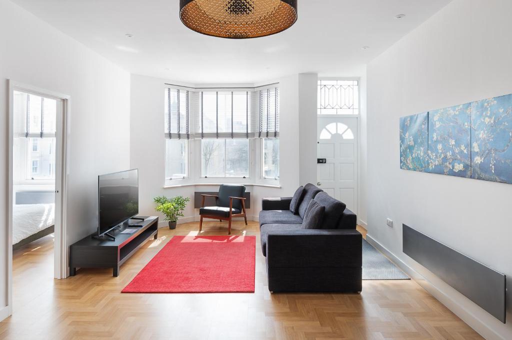 uma sala de estar com um sofá preto e um tapete vermelho em Clarence Square em Brighton & Hove