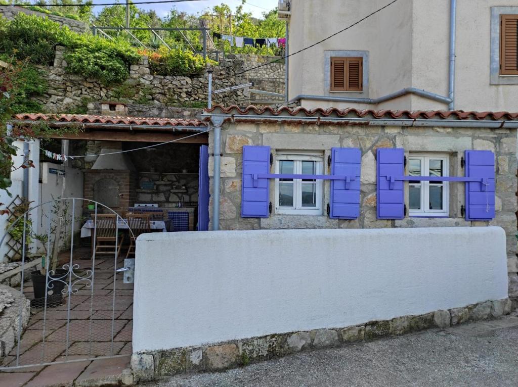 a house with purple shutters on a wall at Apartment Valun 60 in Valun