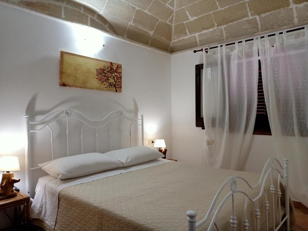 a white bedroom with a white bed and a window at Case Vacanze Mariposa in Favignana