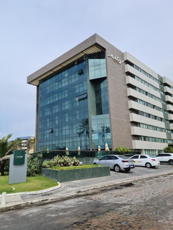 a large building with cars parked in front of it at Ritz Suites Maceió Flat particular Temporada in Maceió