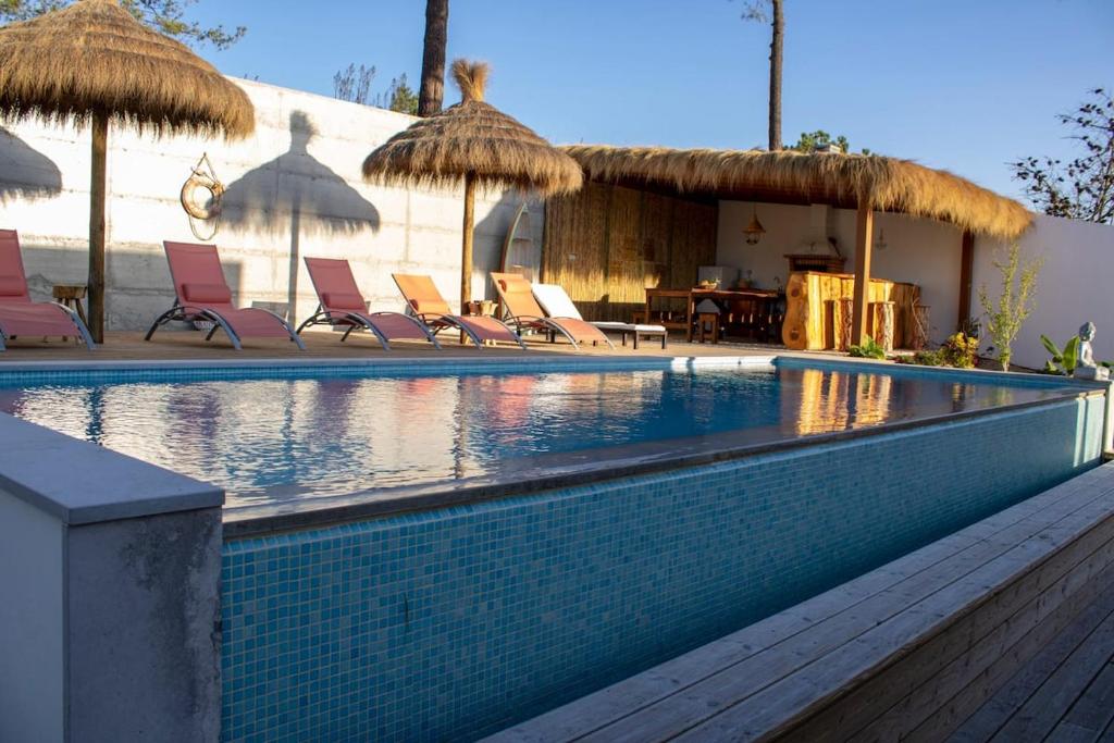 a swimming pool with chairs and umbrellas at Home Beach Dream House in Carvalhal