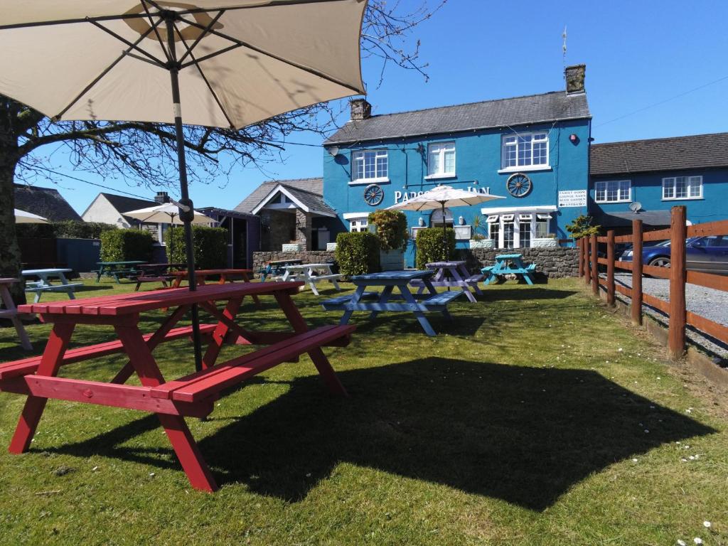 a picnic table with an umbrella in front of a blue building at parsonage farm inn in Tenby