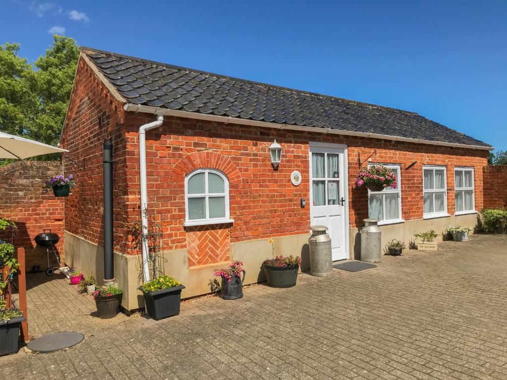 a brick house with potted plants in front of it at The Old Dairy in Hickling