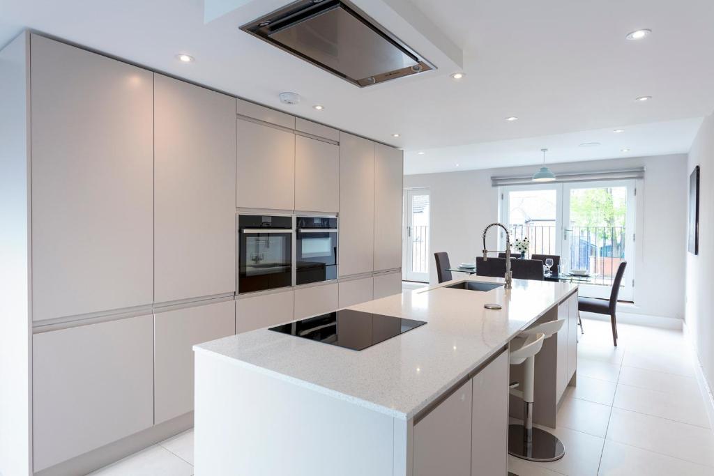 cocina con armarios blancos y encimera blanca en Immaculate Central Windsor Town House with parking en Windsor