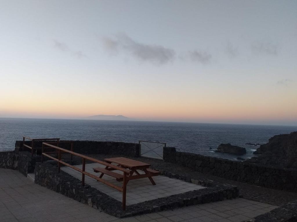 a picnic table sitting on a stone wall near the ocean at Pozo de las Calcosas - El Hierro in Pozo de las Calcosas