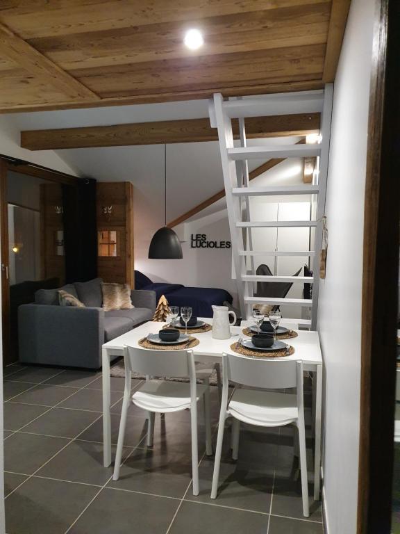 una sala de estar con una mesa y sillas blancas y una escalera en Les Lucioles, en Saint-Jean-de-Sixt