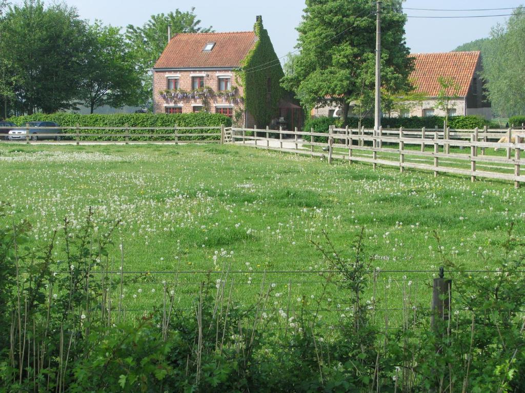 a field of grass with a fence and a house at B&B Le Plat Pays Oostkamp-Brugge in Oostkamp