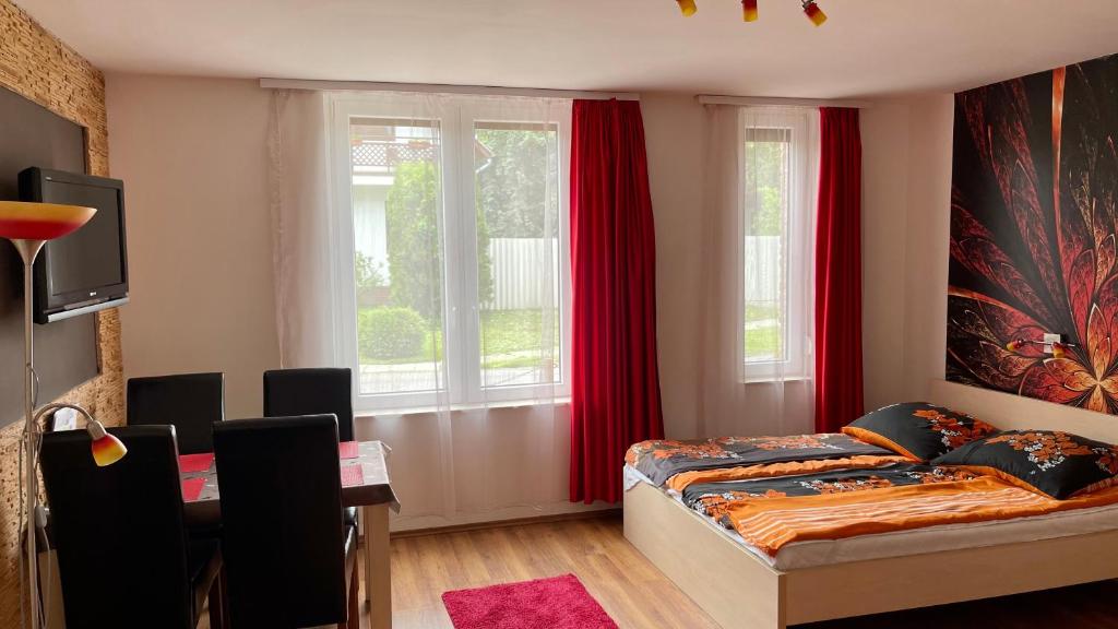 een slaapkamer met een bed en een raam met rode gordijnen bij Gyula Vár Prémium Apartman in Gyula