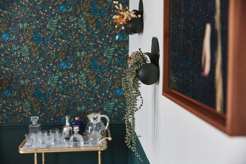 a table with glass items on it next to a painting at Demeure de Manneville - SPA - 1Km des plages de Cabourg in Dives-sur-Mer