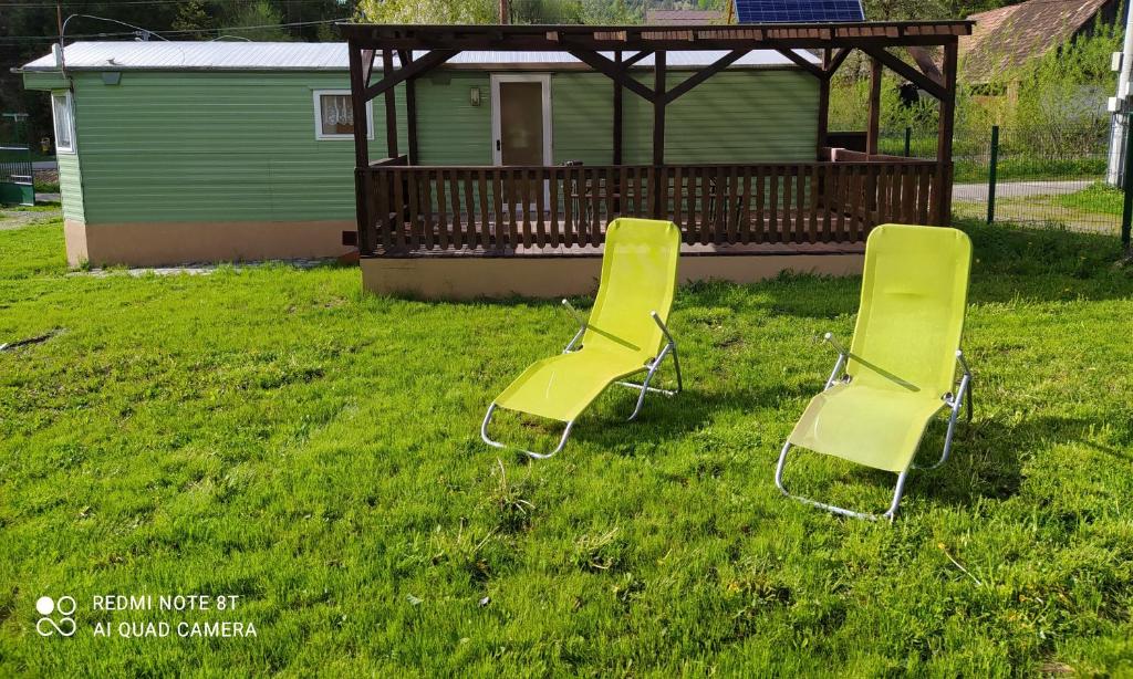 two yellow chairs sitting in the grass near a gazebo at Chata Darwin in Terchová