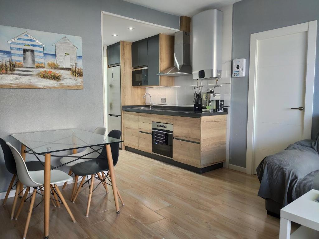 cocina y sala de estar con mesa de cristal y sillas en APARTAMENTO EN BENALBEACH, en Benalmádena