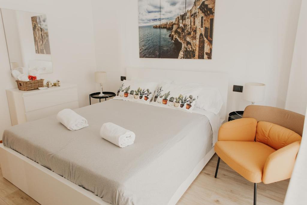 een witte slaapkamer met een bed en een stoel bij Pausa Mare Apartment in Polignano a Mare