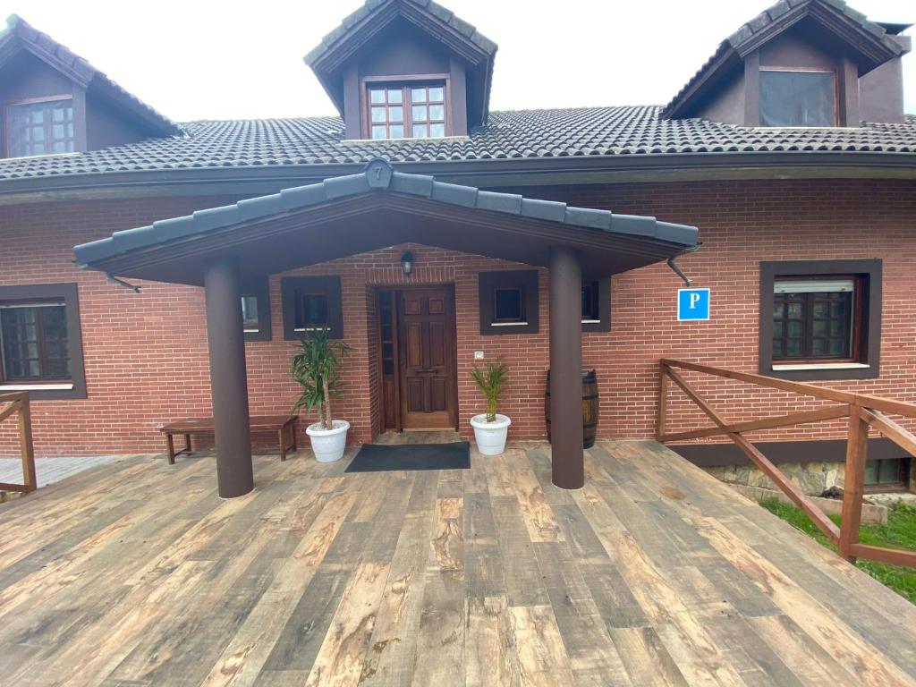 a brick house with a wooden deck in front of it at El ParaÍso de Guriezo in Pomar