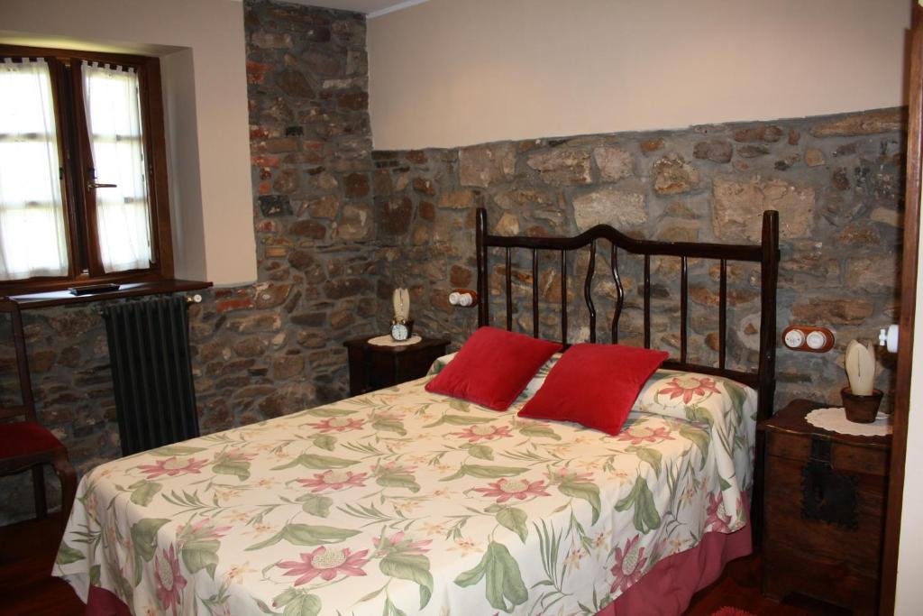a bedroom with a bed with two red pillows at La Casona de Benito in Cudillero