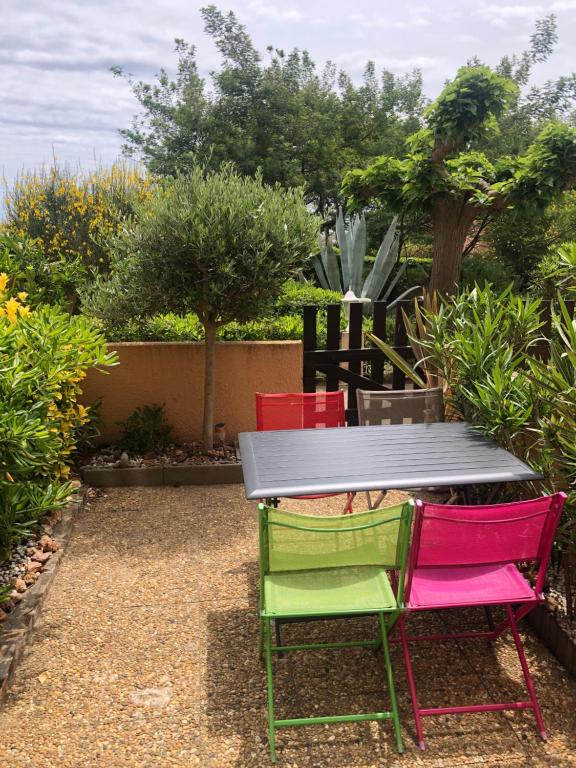 une table avec quatre chaises colorées assises autour de celle-ci dans l'établissement Studio cabine GRUISSAN PLAGE DU GRAZEL, à Gruissan