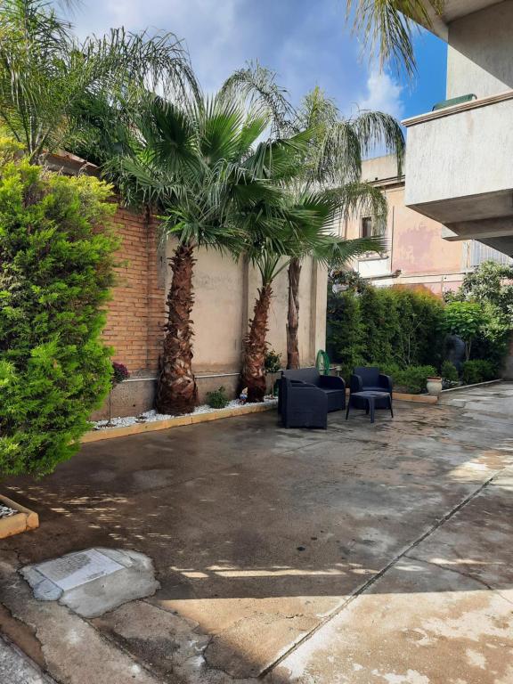 a courtyard with palm trees and couches in a building at Villa Angel in Bovalino Marina