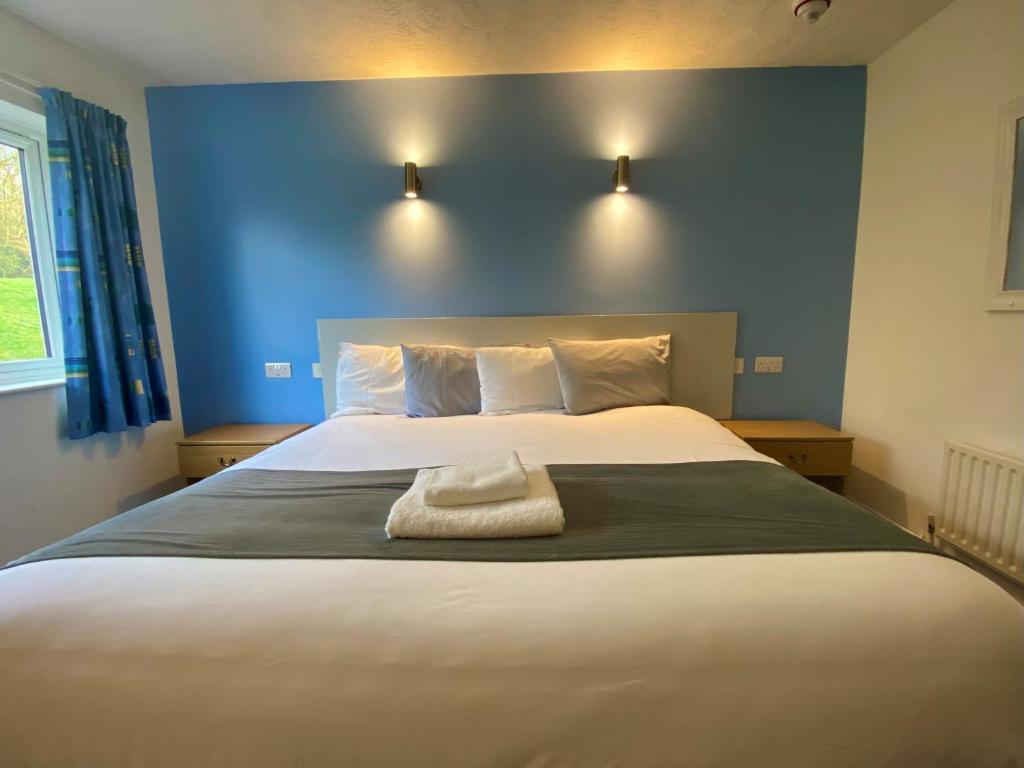 1 dormitorio con 1 cama grande y pared azul en National Badminton Centre Lodge & Health Club en Milton Keynes
