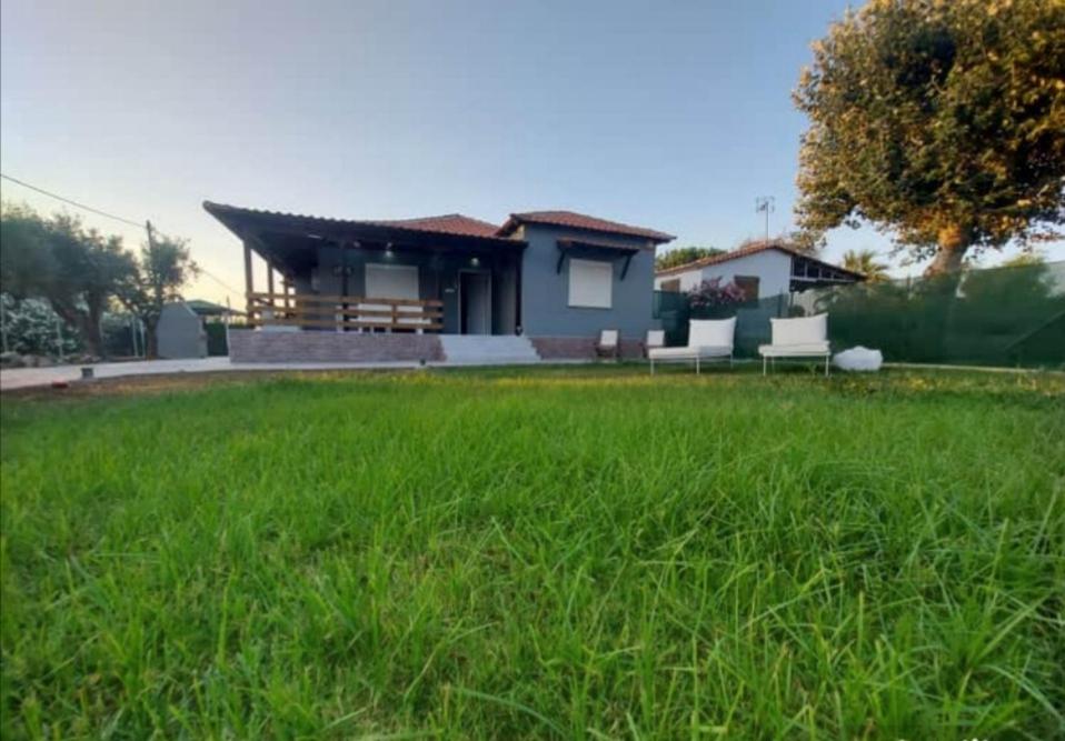 a house with a green lawn in front of it at Chalkidiki Beach House in Nea Potidaea