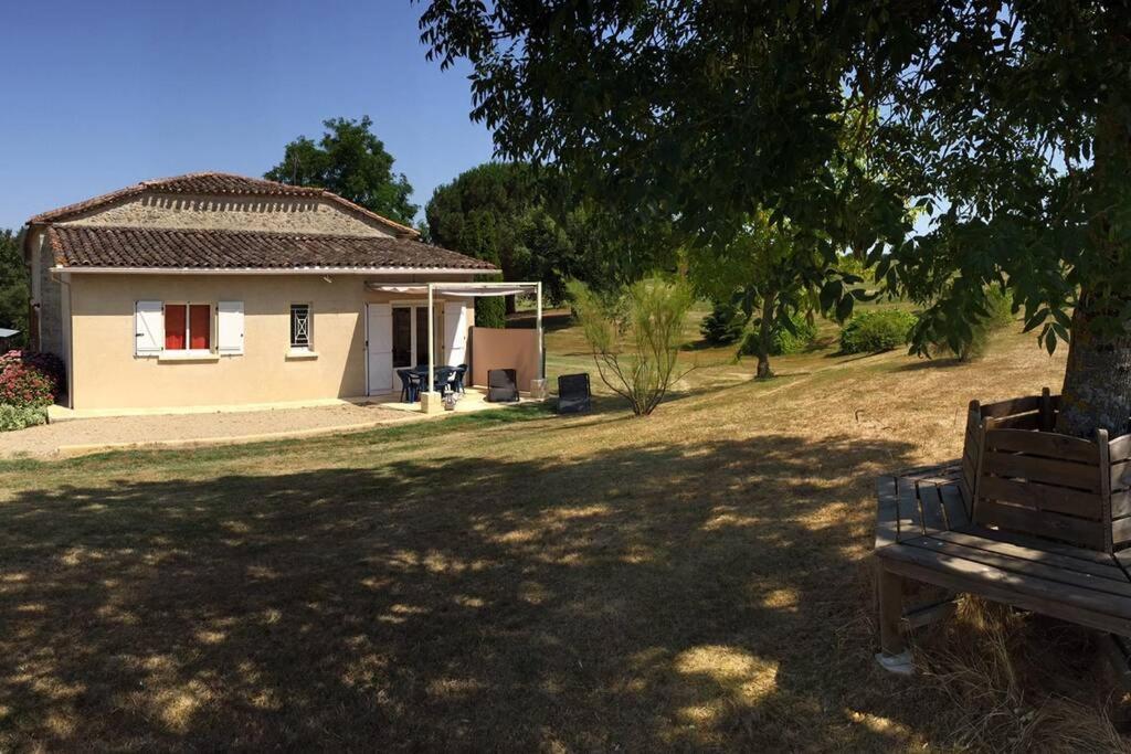 une maison avec un arbre et un banc devant elle dans l'établissement la serenité, à Saint-Vivien-de-Monségur