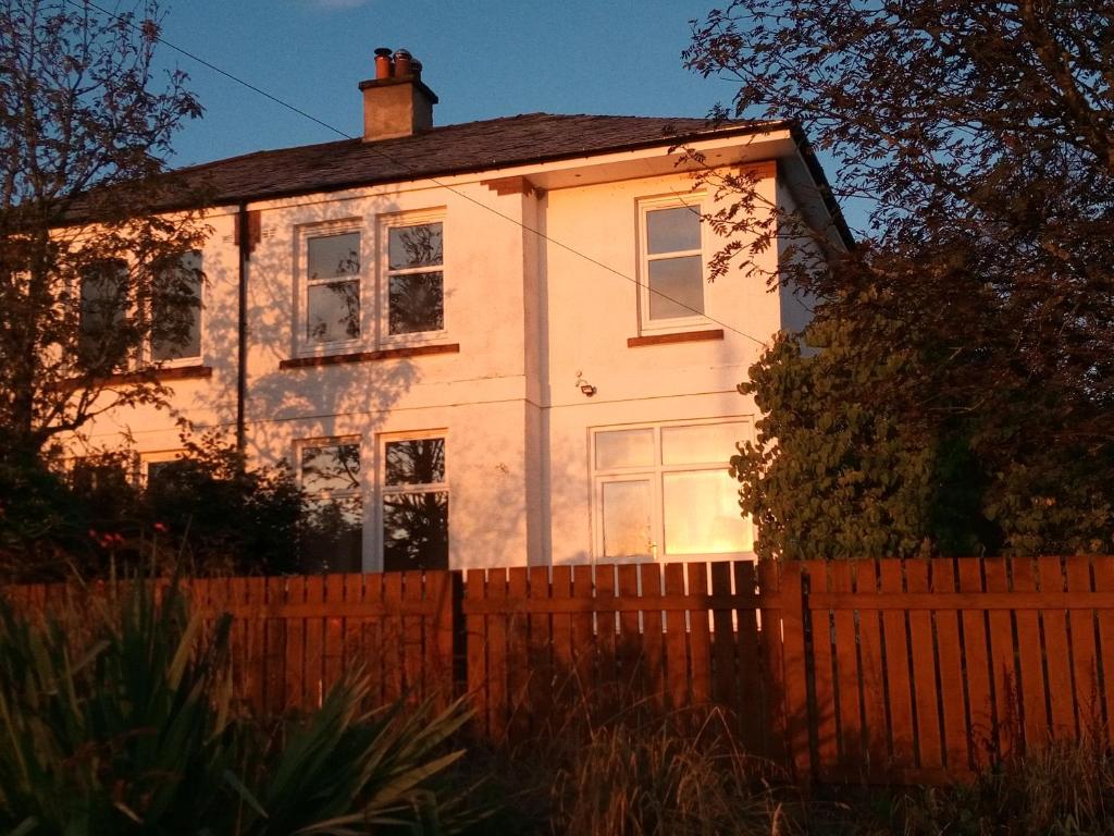 une maison blanche avec une clôture devant elle dans l'établissement Buckieburn - self-catering - rural, à Stirling