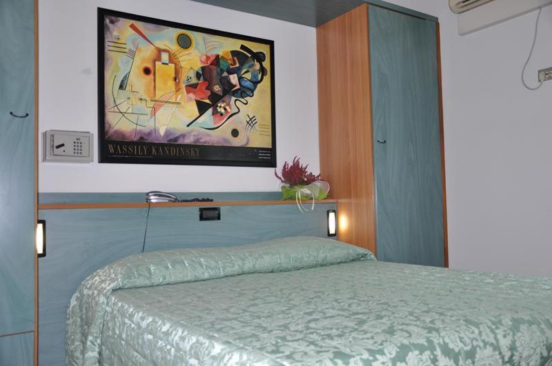 a bedroom with a bed and a painting on the wall at Hotel Bristol in Tirrenia