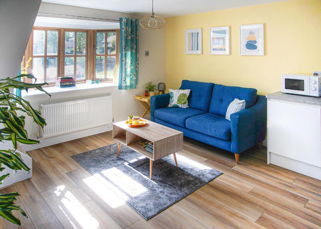 a living room with a blue couch and a table at Walking distance to hospital and town with free off-road parking in Bury Saint Edmunds