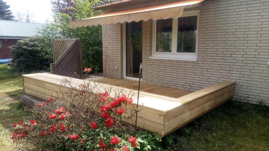 eine Holzterrasse auf einem Haus mit roten Blumen in der Unterkunft Sommerhaus in Eggstedt