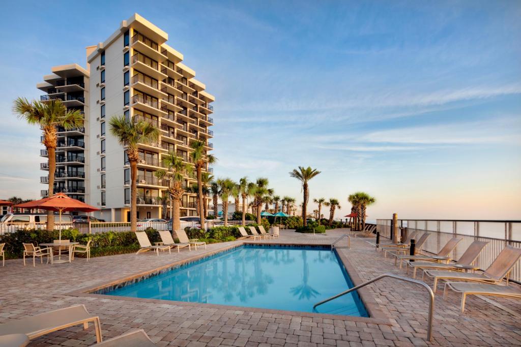 a swimming pool with chairs and a building at Nautilus Inn - Daytona Beach in Daytona Beach