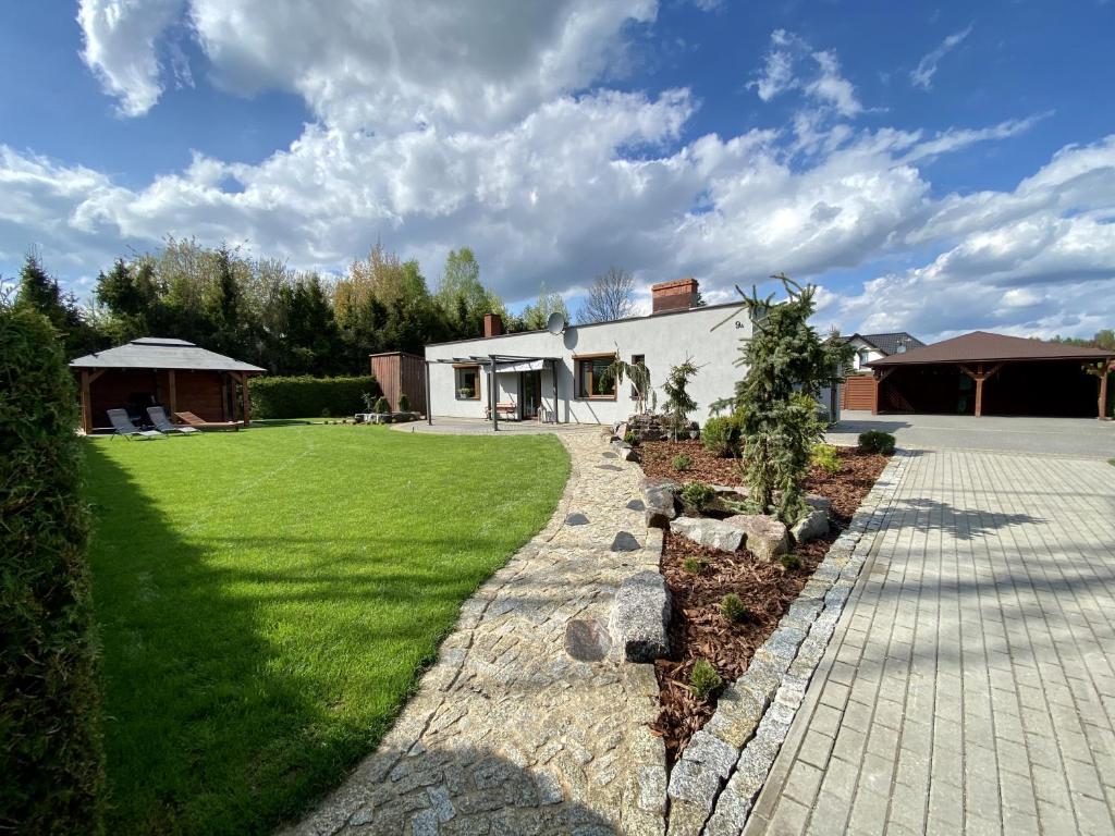 un patio con una casa y un campo de hierba en Kameralny Domek(jezioro, las, klimatyzacja, Wi-fi), en Czluchów