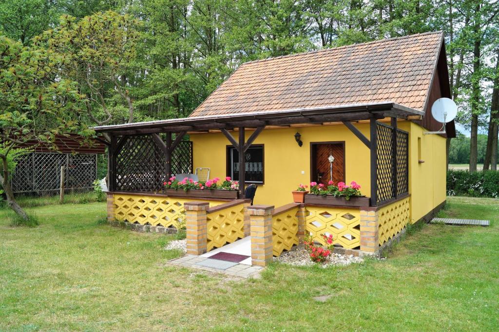 uma pequena casa amarela com flores num quintal em Ferienhaus am Bismarckturm in Burg em Burg