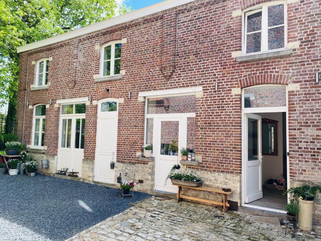 a brick building with white doors and a bench at Cosy house in a charming village in Beauvechain