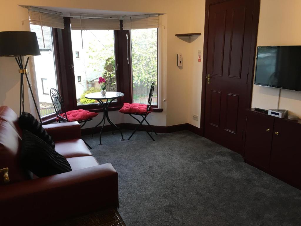 a living room with a couch and a tv and a table at Modern 1 Bedroom Apartment central Inverness city in Inverness