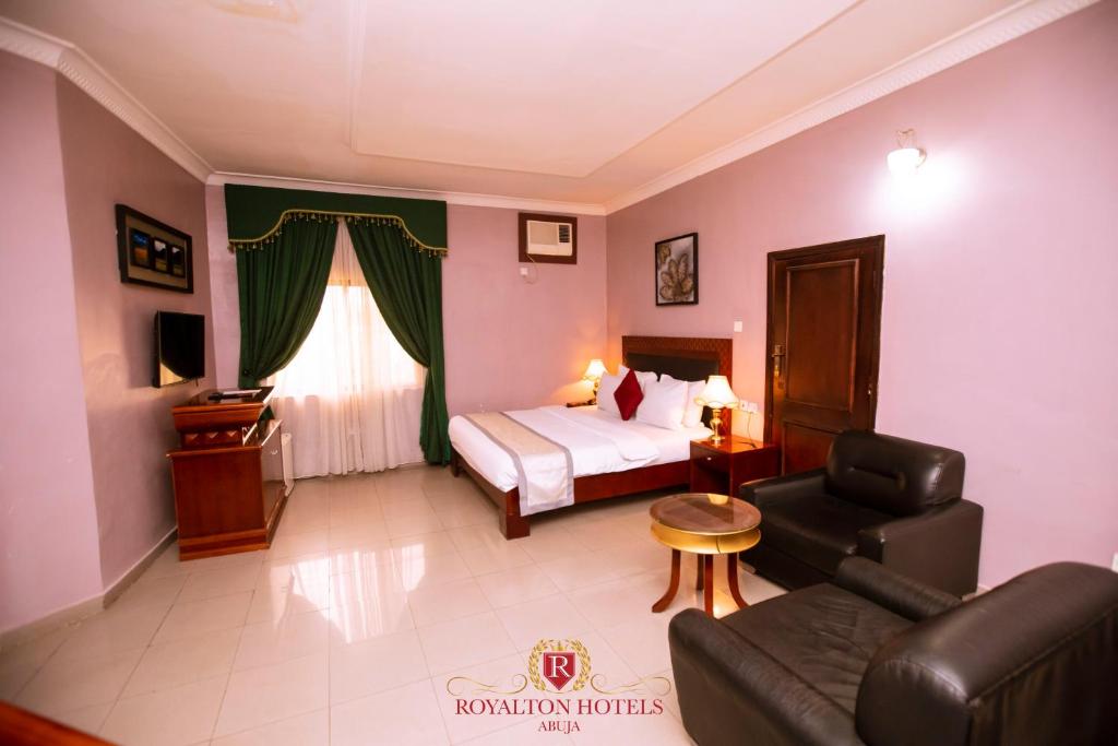 a hotel room with a bed and a chair and a couch at Royalton Hotels Abuja in Abuja