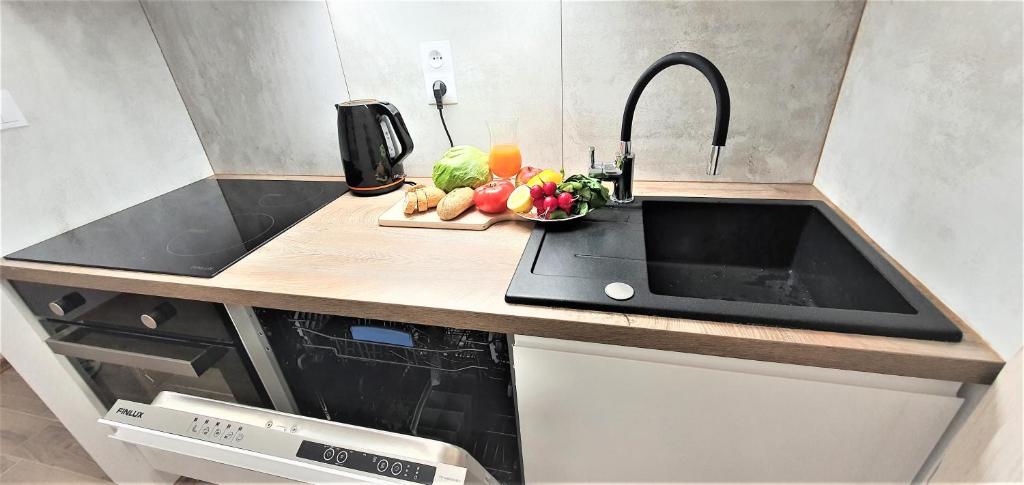- un comptoir de cuisine avec un évier et des fruits sur une planche de découpe dans l'établissement Apartament Altheide, à Polanica-Zdrój