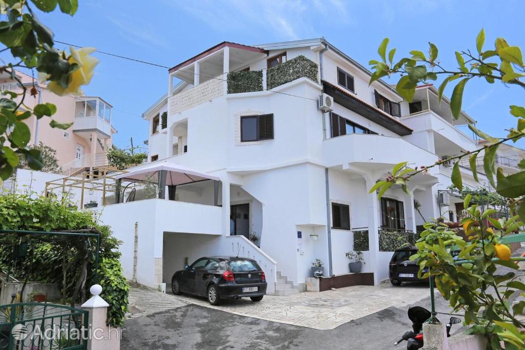 ein weißes Haus mit einem davor geparkt in der Unterkunft Apartments Bagaric in Trogir