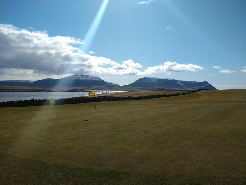 uma vista para um campo de golfe com um arco-íris em Orkney Lux Lodges - Hamnavoe em Stromness