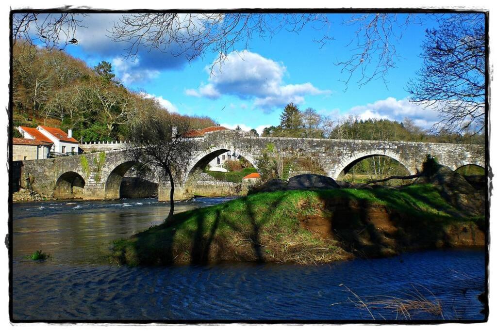 un puente de piedra sobre un río en una ciudad en Moderno apartamento en el Camino de Fisterra, en Negreira