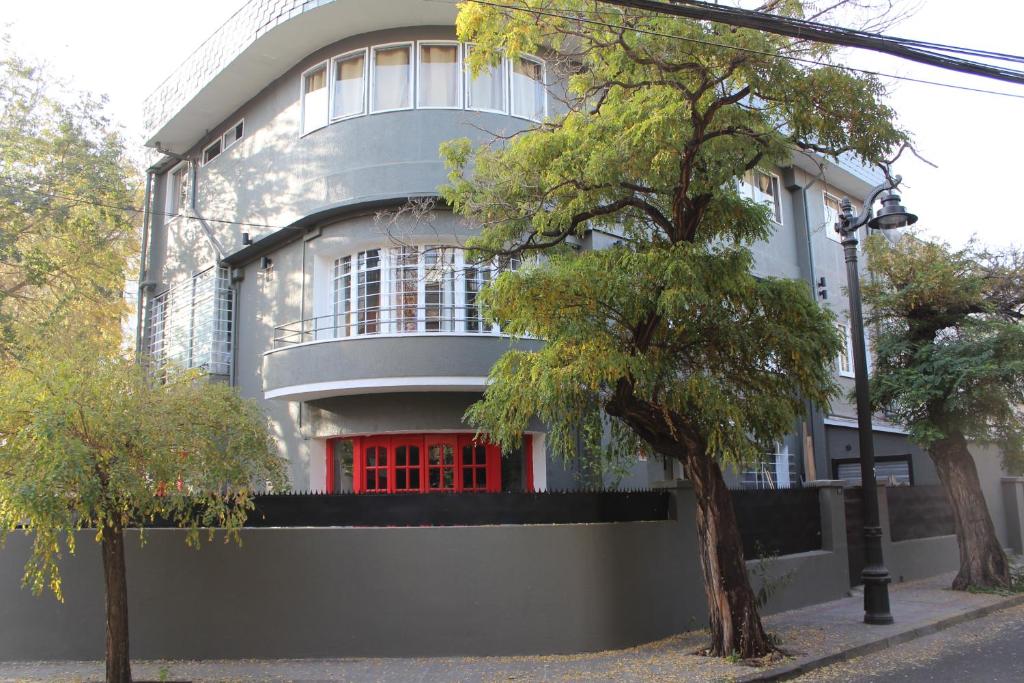 a white building with red doors and a tree at Aji Hostel in Santiago