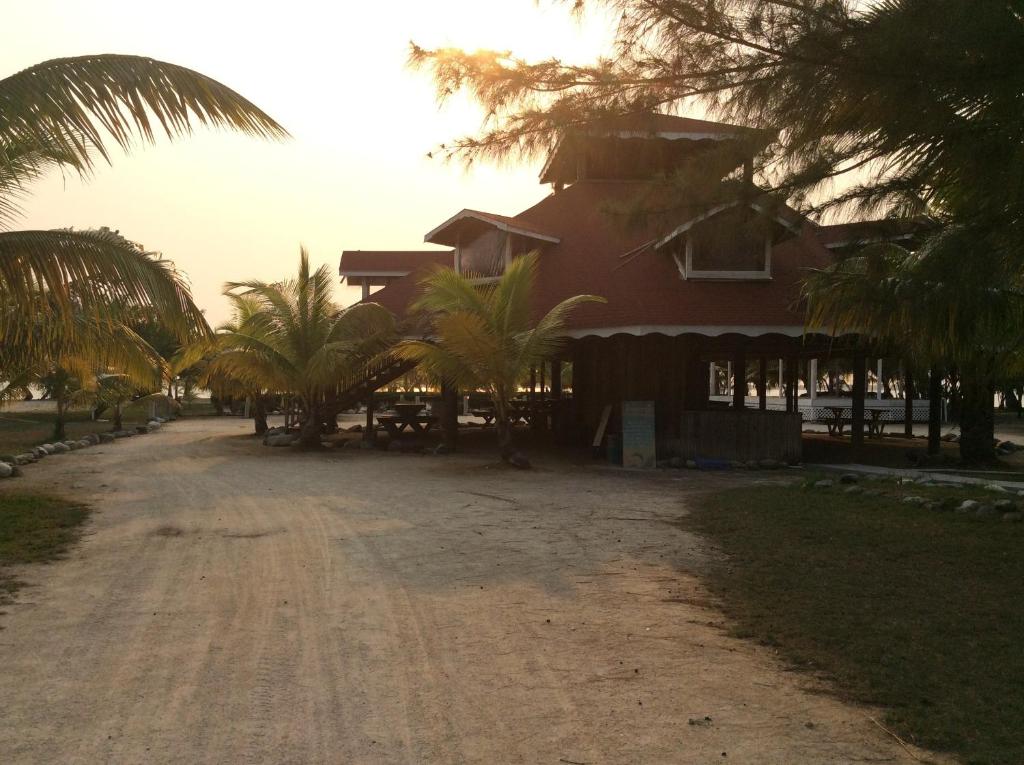 une maison avec des palmiers en face d'un chemin de terre dans l'établissement Sea Eye Hotel - Laguna Building, à Utila