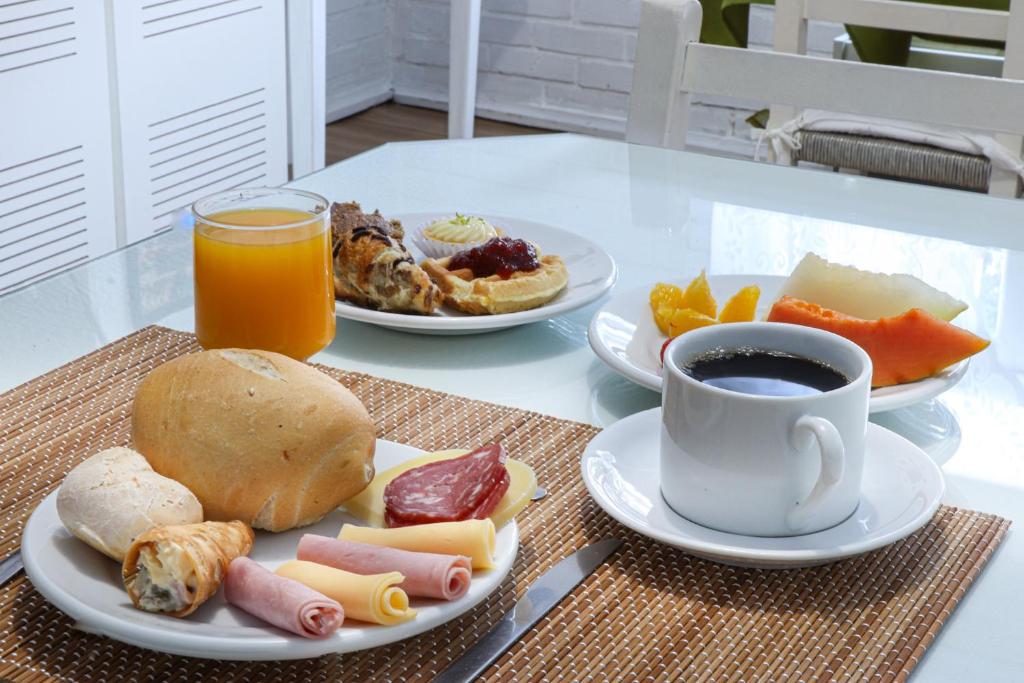 a table with plates of food and a cup of coffee at Pousada Tia Eni in Gramado