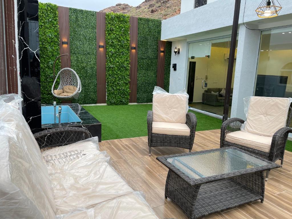 een patio met een bank, stoelen en een heg bij Luxury OVO Roof Villa in Taif