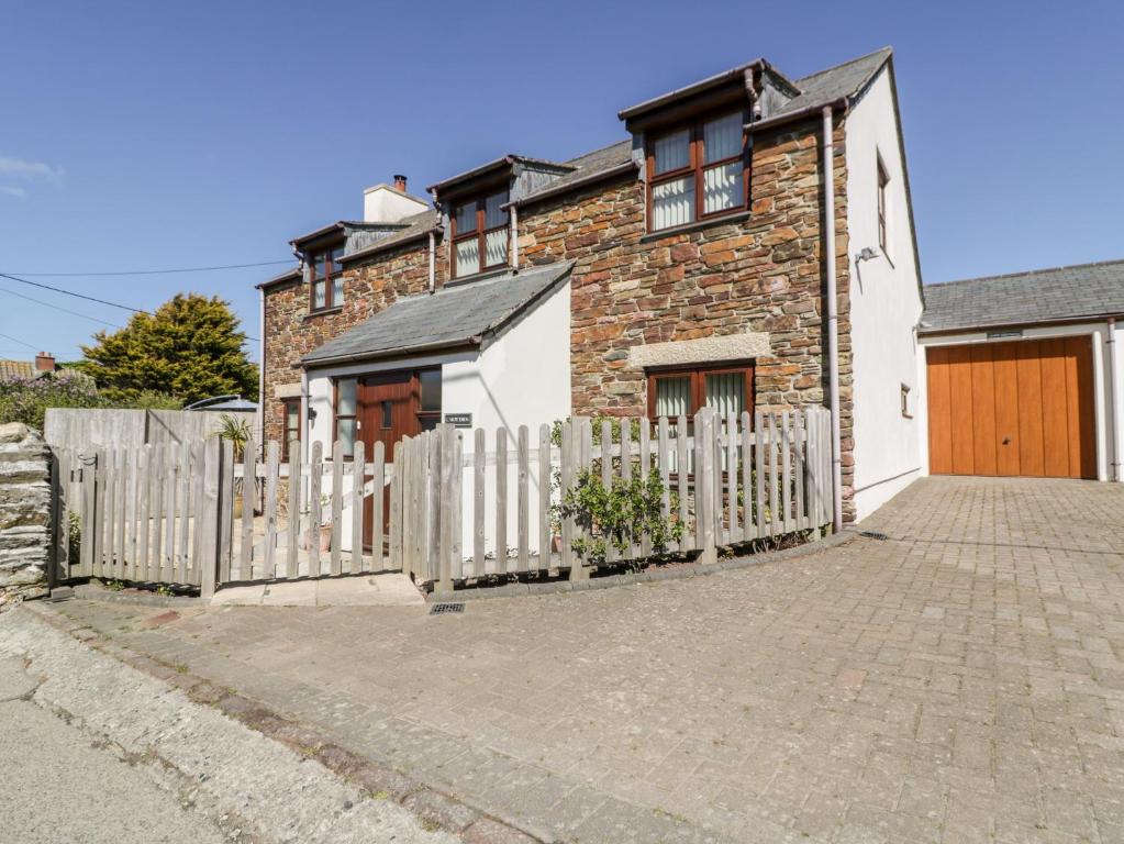 a brick house with a white picket fence at Carpe Diem in Crantock
