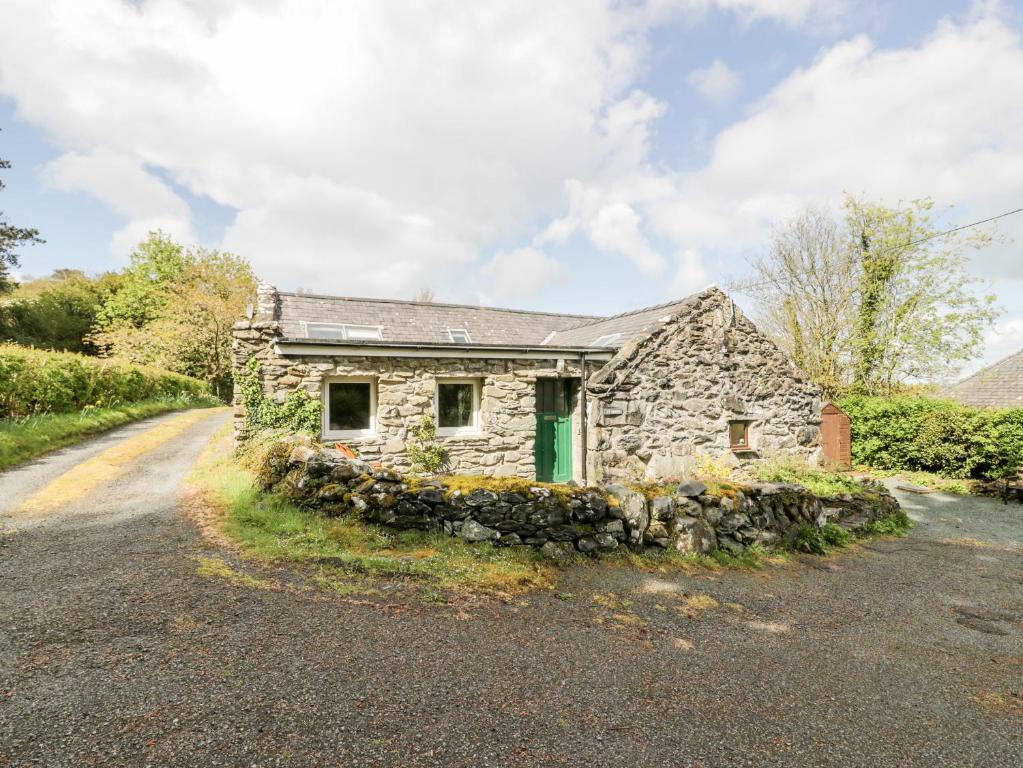 una vieja casa de piedra al lado de una carretera en Ty Cerrig, en Llanbedr