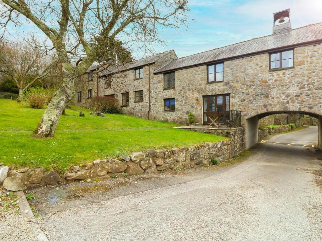 an old stone house with an archway and a road at Bell Cottage in Penzance